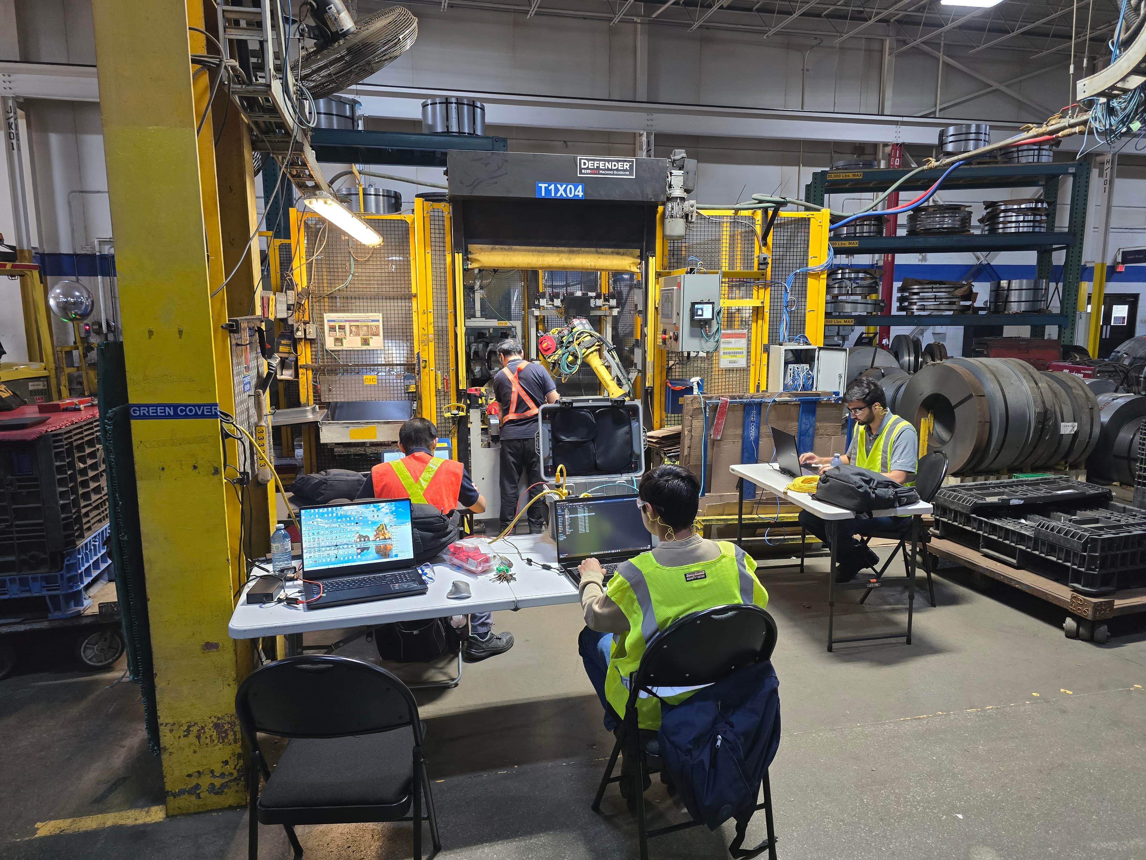 Technicians commissioning a press automation cell with laptops on site