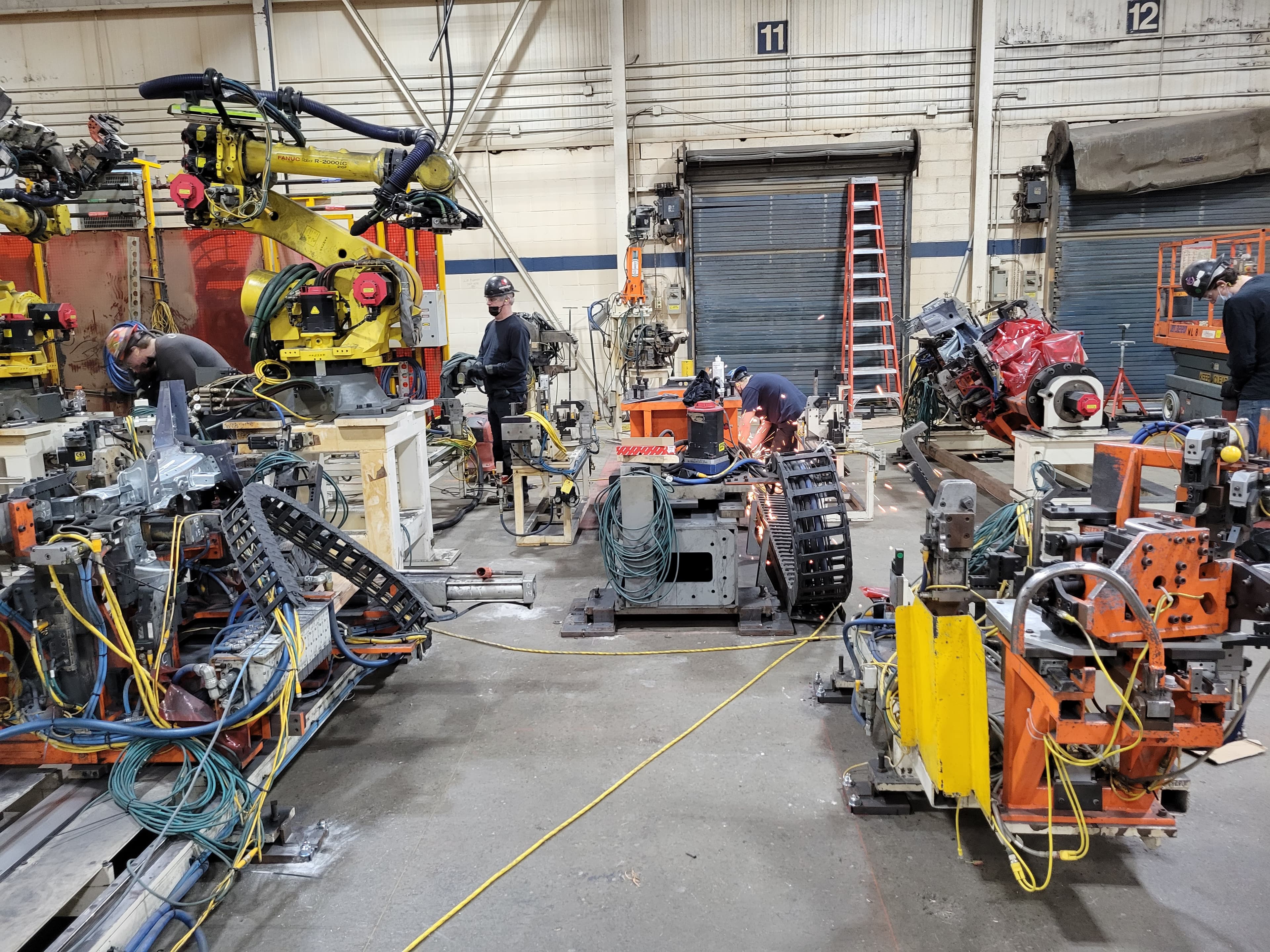 Technicians commissioning a row of FANUC robots on the production floor